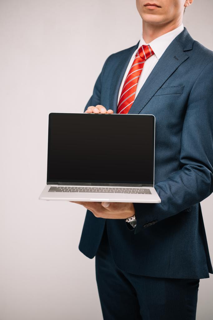 vue recadrée de l'homme d'affaires en costume présentant ordinateur portable isolé sur gris
 - Photo, image