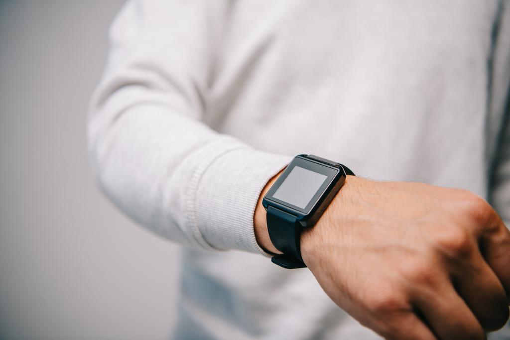 vista ritagliata dell'uomo con smartwatch a portata di mano isolato su grigio
 - Foto, immagini
