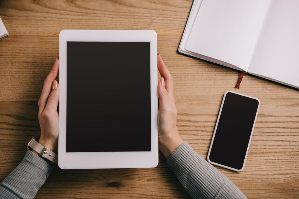 Ausgeschnittene Ansicht einer Geschäftsfrau mit digitalem Tablet am Arbeitsplatz mit Smartphone und Notebook - Foto, Bild