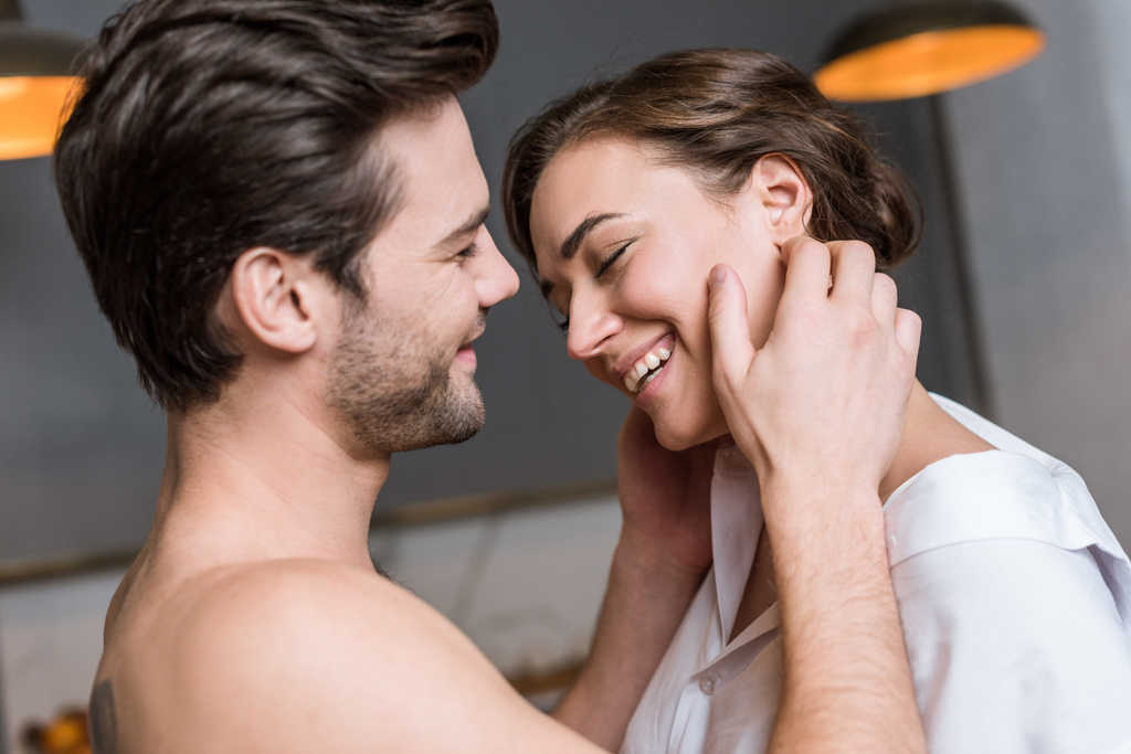 adult tender man touching girl in shirt and smiling at home - Photo, Image