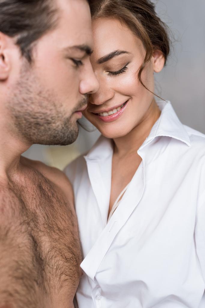 Close up van aantrekkelijke vrouw die lacht met gesloten ogen in de buurt van shirtless vriendje - Foto, afbeelding
