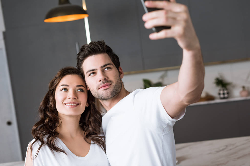 hermosa novia y guapo novio tomando selfie en casa
 - Foto, Imagen