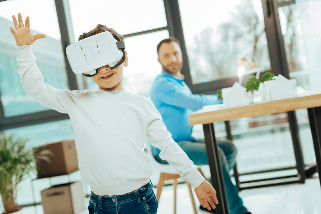 Emotionele jongen zijn handen zetten tijdens het gebruik van virtual reality bril - Foto, afbeelding