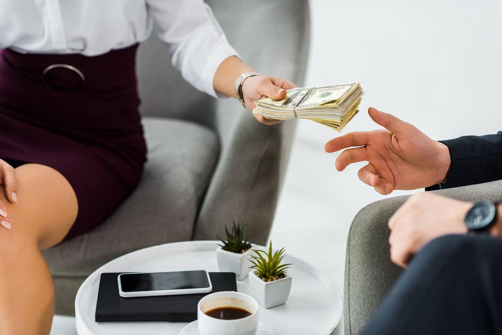 обрезанный взгляд бизнесвумен дает деньги бизнесмену в офисе
  - Фото, изображение