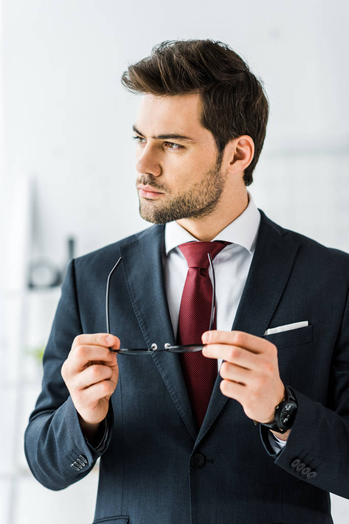 όμορφος επιχειρηματία σε επίσημη ένδυση βάζει γυαλιά στο γραφείο - Φωτογραφία, εικόνα