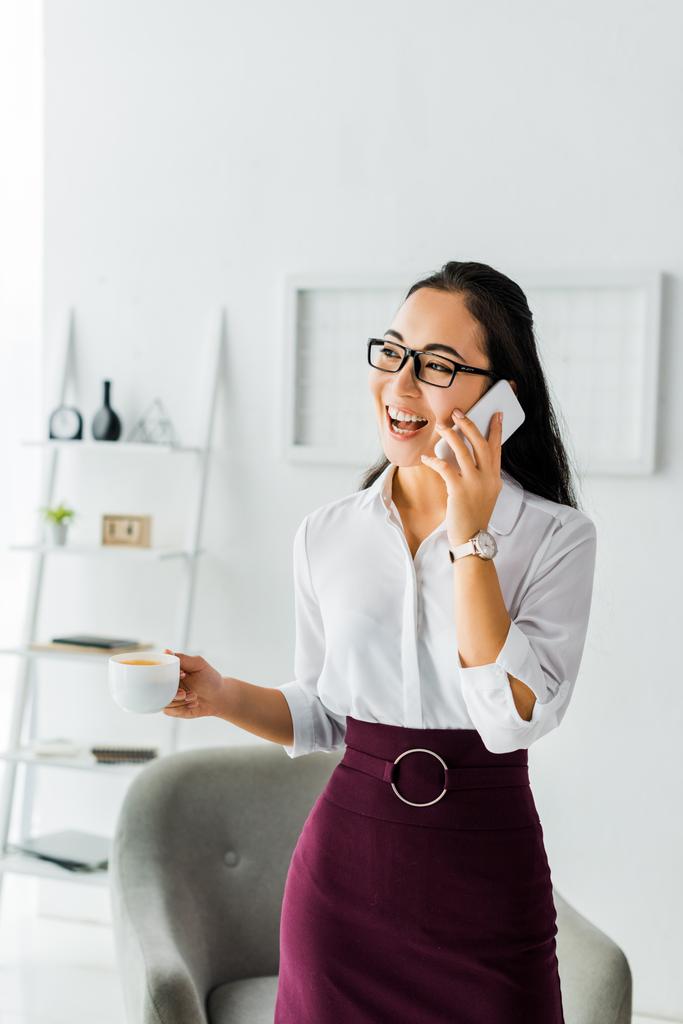 ofiste kahve molası verirken akıllı telefonda konuşan güzel gülen asyalı iş kadını - Fotoğraf, Görsel