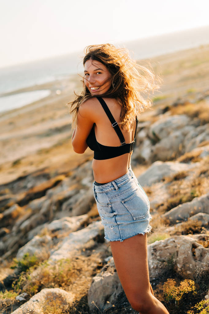 Модний портрет красивої розслабленої жінки з джинсами на пляжі на заході сонця, ретро і меланхолійний стиль
. - Фото, зображення