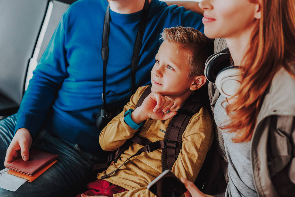 Huomaavainen poika odottaa lentoa vanhempien kanssa
 - Valokuva, kuva