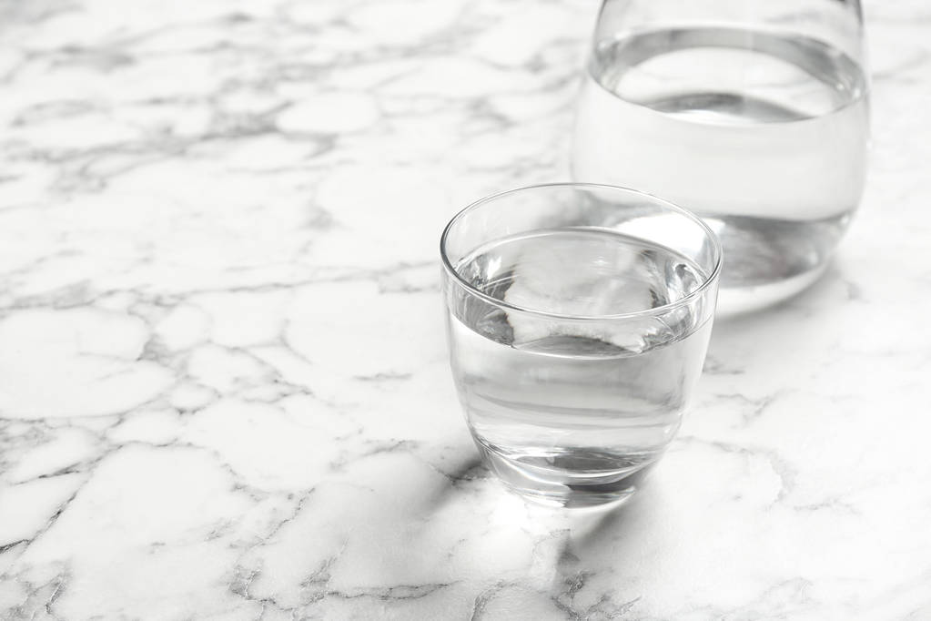 Glas und Kanne mit Süßwasser auf Marmortisch. Raum für Text - Foto, Bild