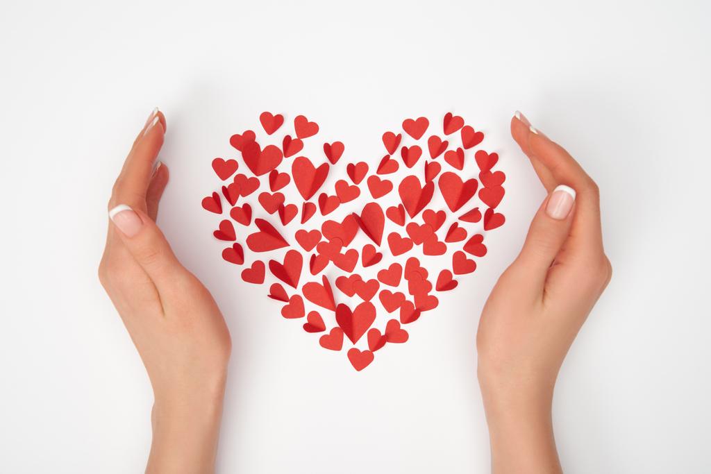 περικοπεί θέα γυναικεία χέρια κοντά σε διάταξη των μικρών κόκκινο χαρτί σε σχήμα καρδιάς κομμένα καρδιές - Φωτογραφία, εικόνα