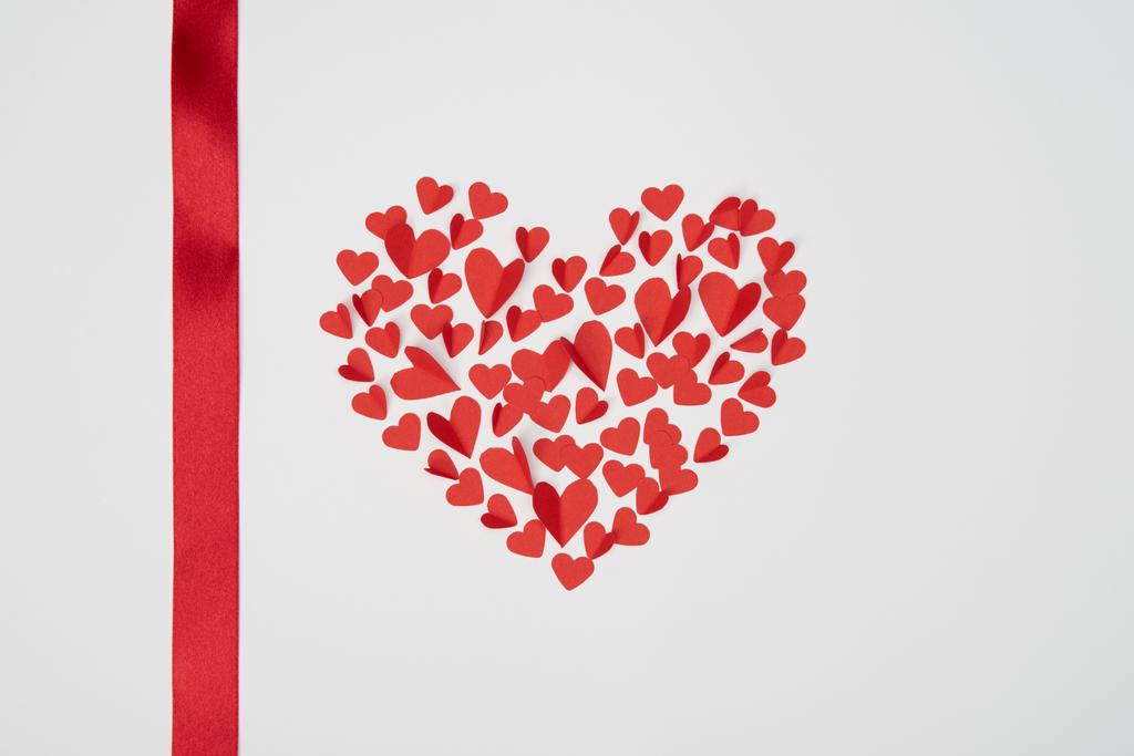 hart-vormige regeling van kleine rode papieren harten met satijn lint knippen op witte achtergrond - Foto, afbeelding