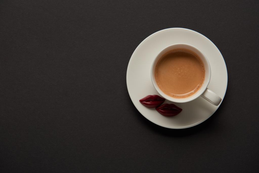 vue du dessus de la tasse avec café et lèvres chocolat sur soucoupe sur fond noir
 - Photo, image