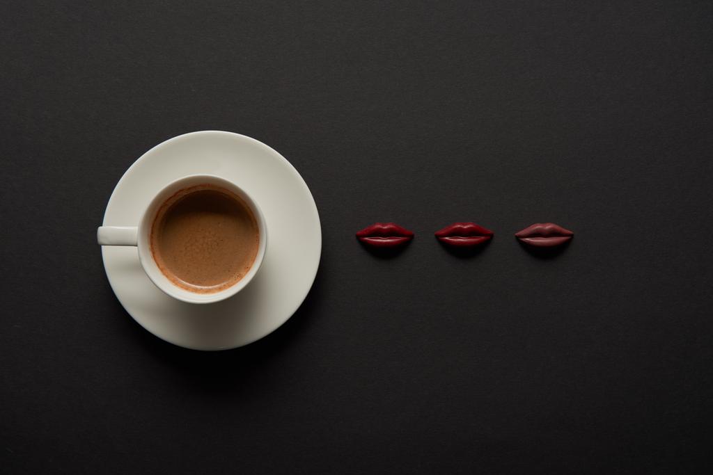 vista superior de la taza de café cerca de los labios de chocolate sobre fondo negro
 - Foto, Imagen