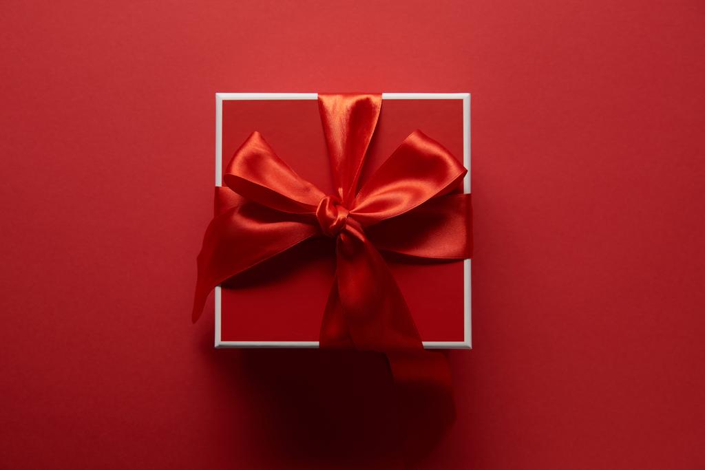 top view of present with silk ribbon on red background - Photo, Image