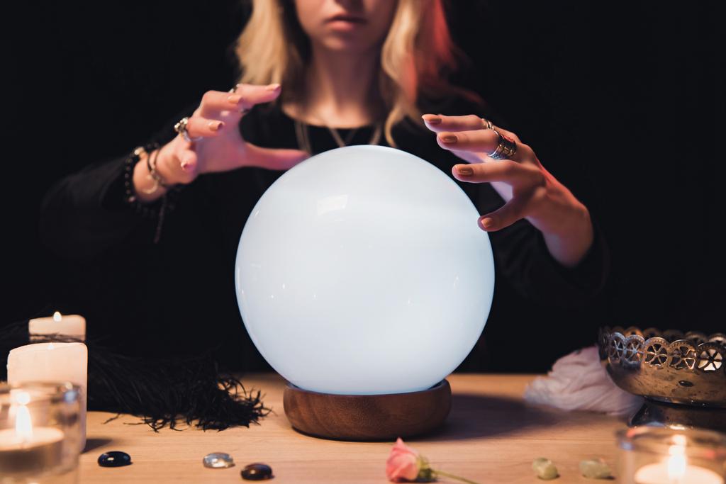 vista cortada de mãos esotéricas femininas segurando acima bola de cristal mágico isolado em preto
 - Foto, Imagem