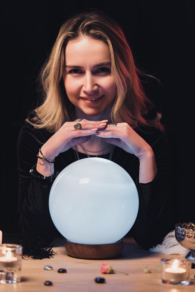 attraente mano esoterica tenuta sopra sfera di cristallo vicino a candele isolate su nero
 - Foto, immagini