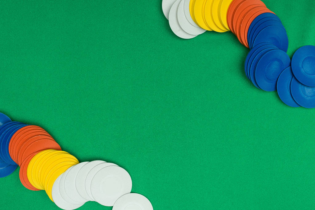 pohled shora zelené pokerového stolu s vícebarevné čipy pro hru - Fotografie, Obrázek