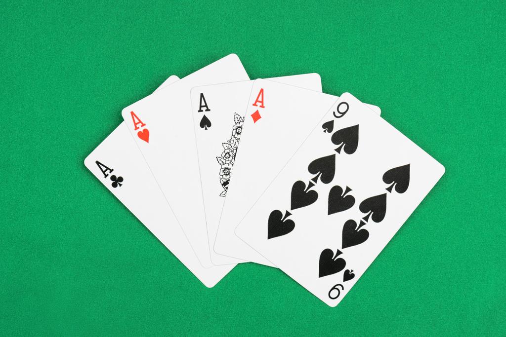 вид зеленого покерного стола с развернутыми игральными картами, четырьмя тузами и девятью
 - Фото, изображение