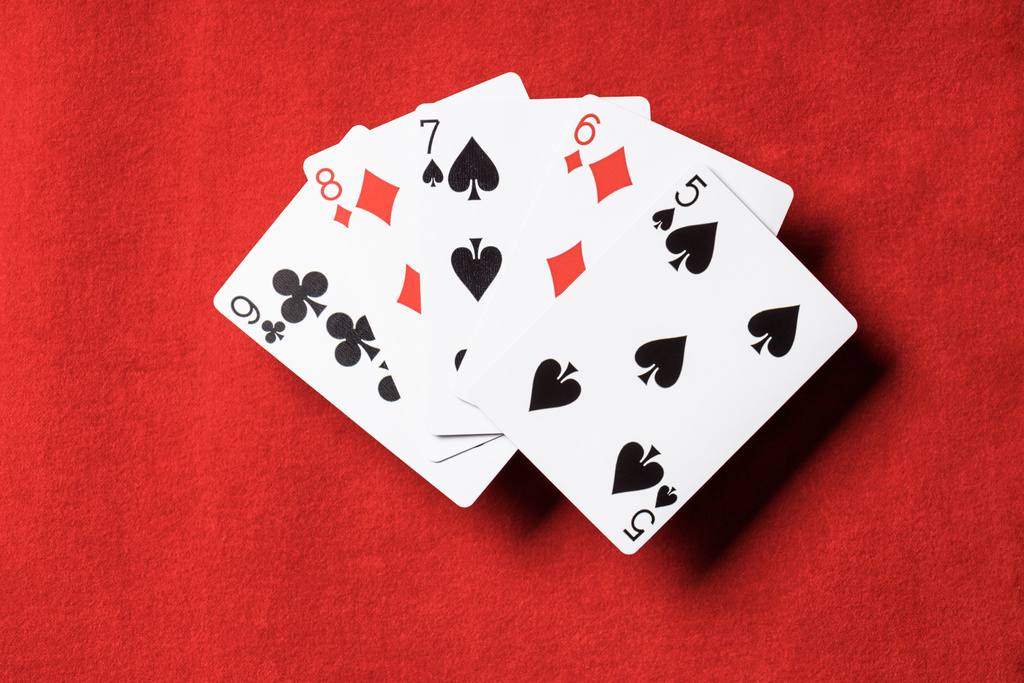 bovenaanzicht van rode tabel en ongevouwen speelkaarten met verschillende kleuren - Foto, afbeelding
