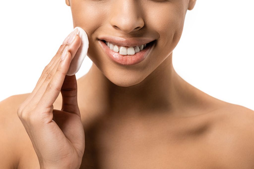 tiro recortado de sorrir jovem afro-americana limpeza rosto com disco de algodão isolado no branco
 - Foto, Imagem