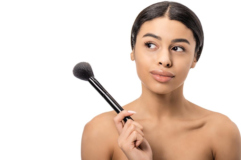 Cher jeune femme africaine américaine nue tenant pinceau de maquillage et regardant loin isolé sur blanc
 - Photo, image