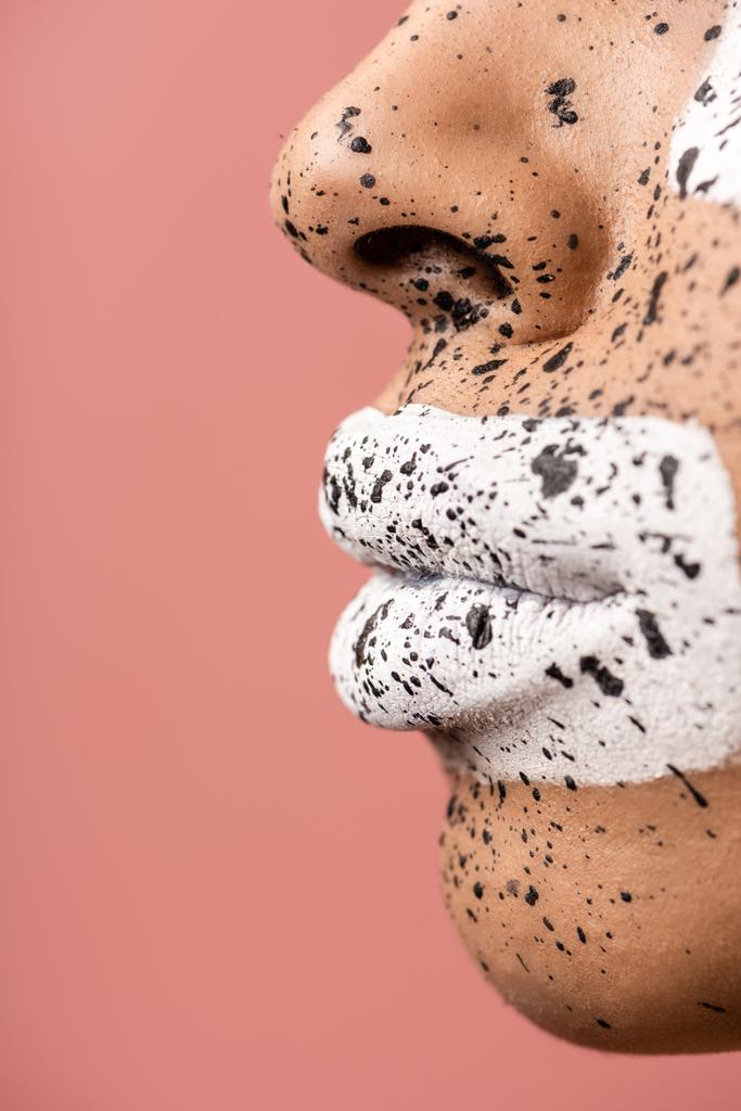 close-up view of female lips with white paint and face with brown splashes isolated on pink - Photo, Image