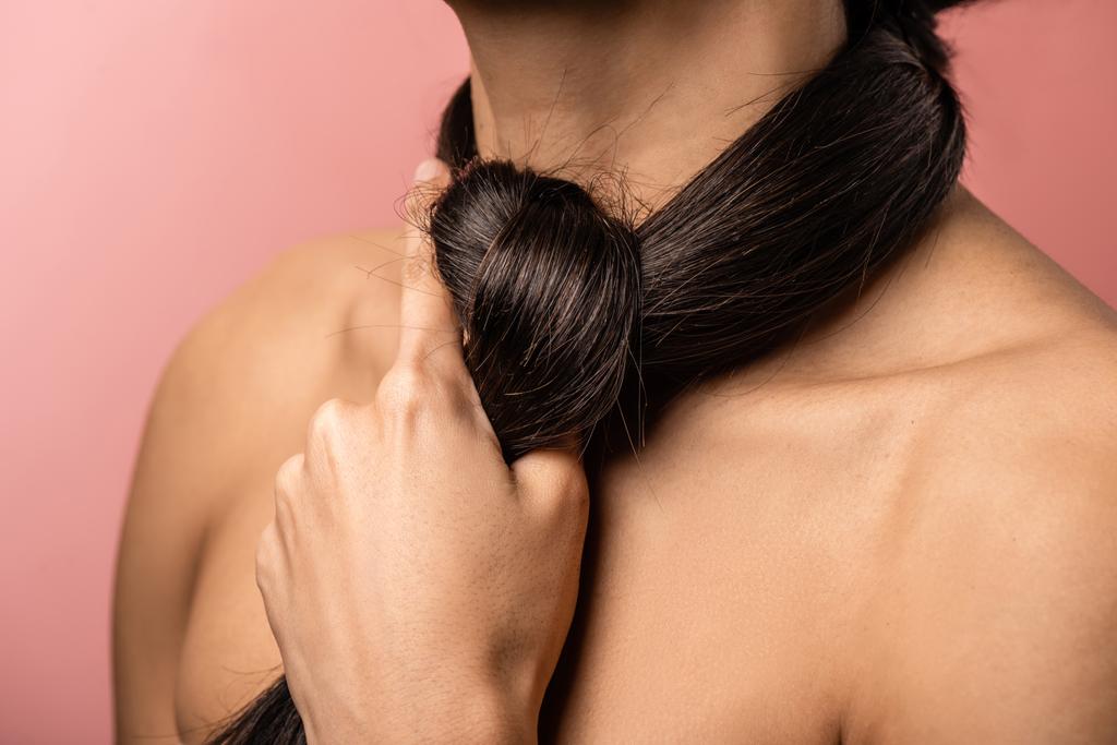 cropped shot of naked female shoulders and long brunette hair around neck isolated on pink - Photo, Image