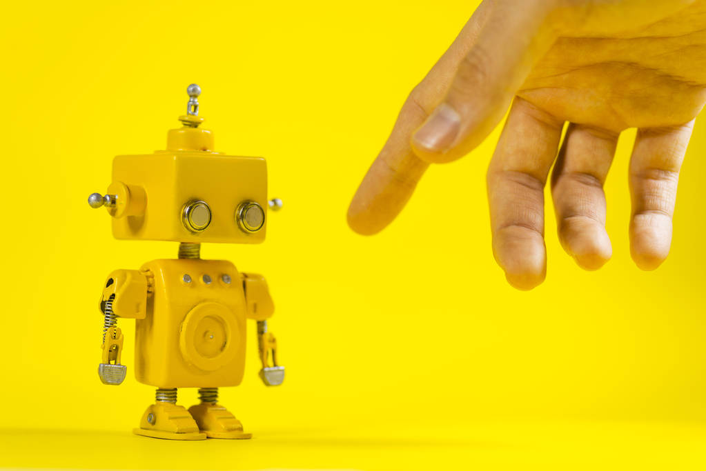 Schattige, handgemaakte gele robot op een gele achtergrond. - Foto, afbeelding