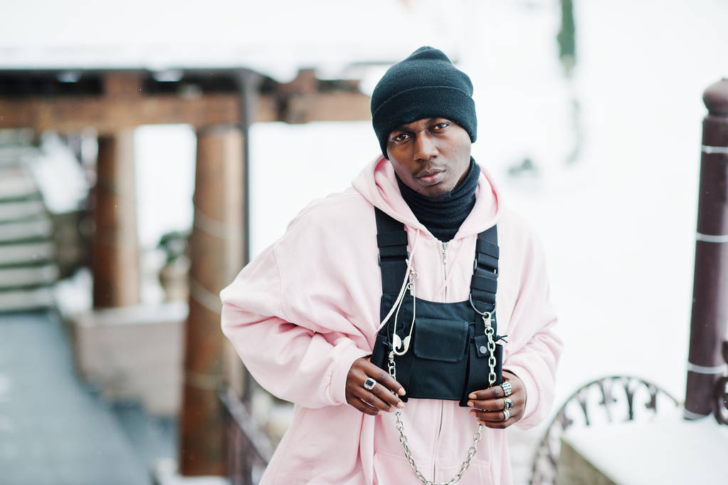 Stijlvolle stedelijke stijl Afro-Amerikaanse man in roze hoodie gesteld bij winterdag. - Foto, afbeelding