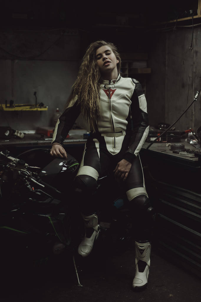 Garajda motosiklet tamir eden uzun saçlı güzel bir kız. - Fotoğraf, Görsel