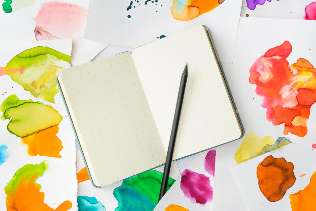top view of white notebook with pencil on background with abstract watercolor paintings - Photo, Image