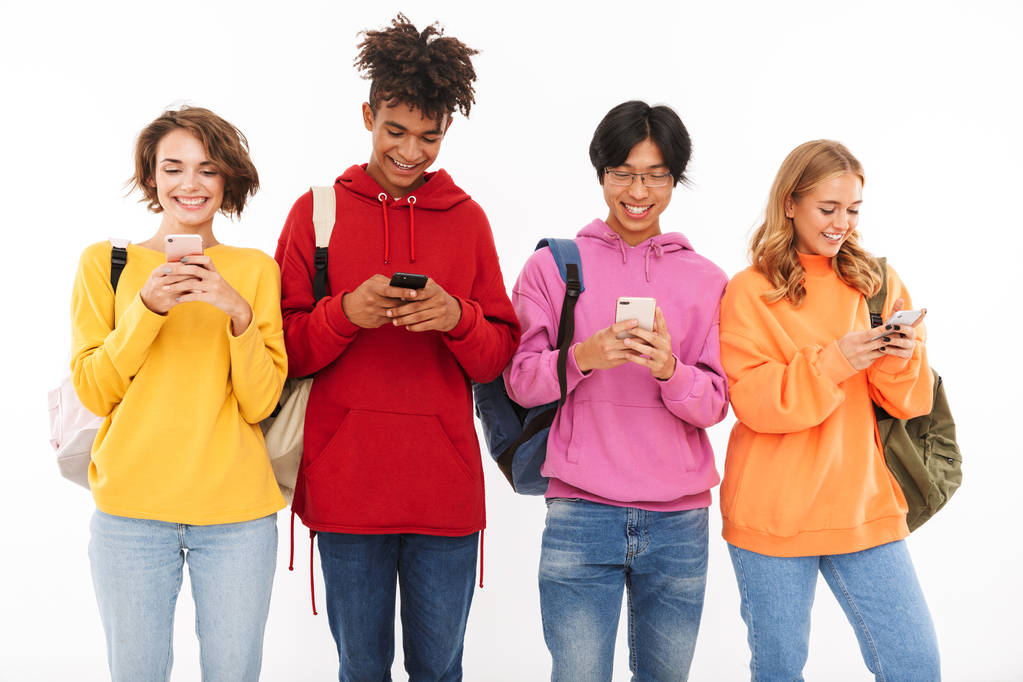 Gruppe fröhlicher Teenager isoliert auf weißem Hintergrund, mit Rucksäcken und Mobiltelefonen - Foto, Bild