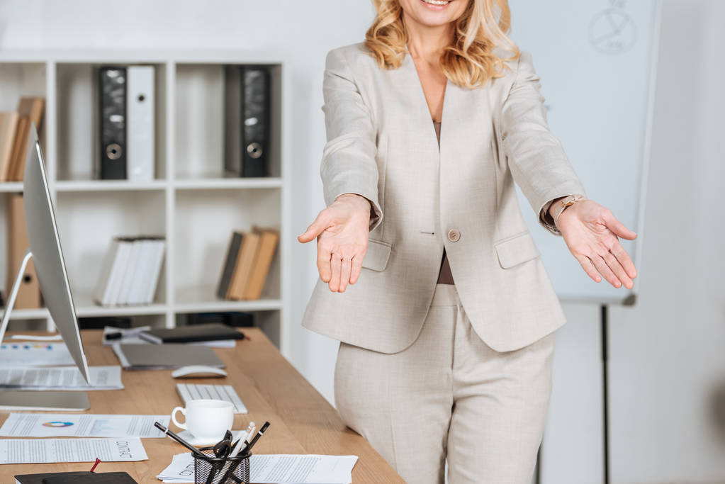 recortado disparo de sonriente mujer de negocios saludando a alguien y haciendo un gesto con las manos en la oficina
 - Foto, imagen