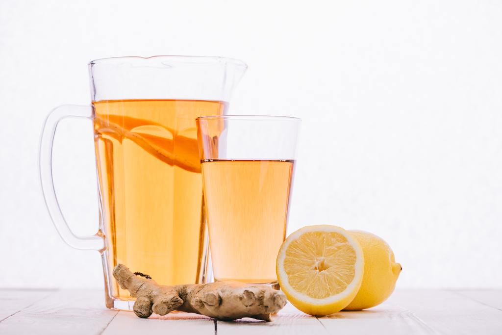 чай с лимоном и корень имбиря в стекле и банка на деревянном столе изолированы на белом
 - Фото, изображение