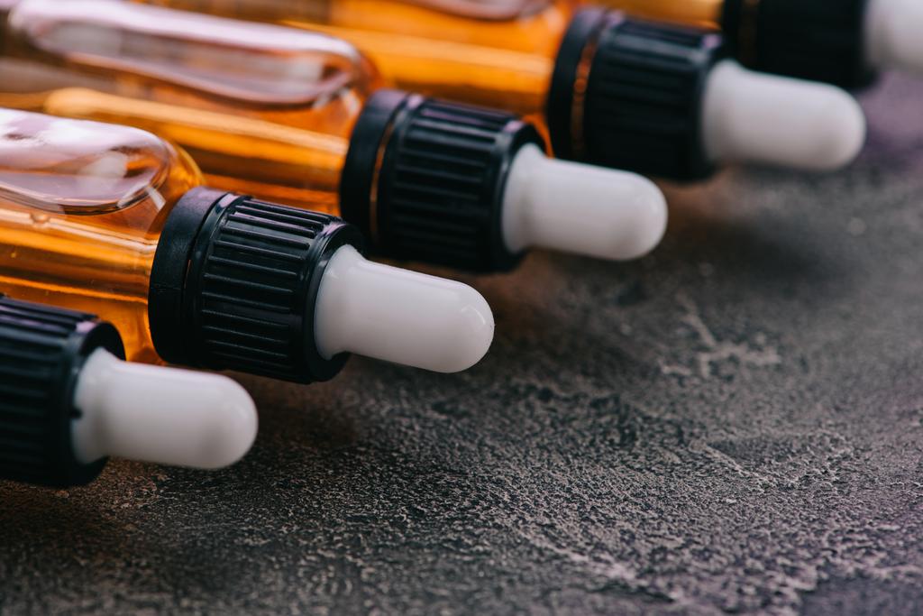 селективный фокус масла каннабидола в бутылках с капельницами на серой поверхности
 - Фото, изображение