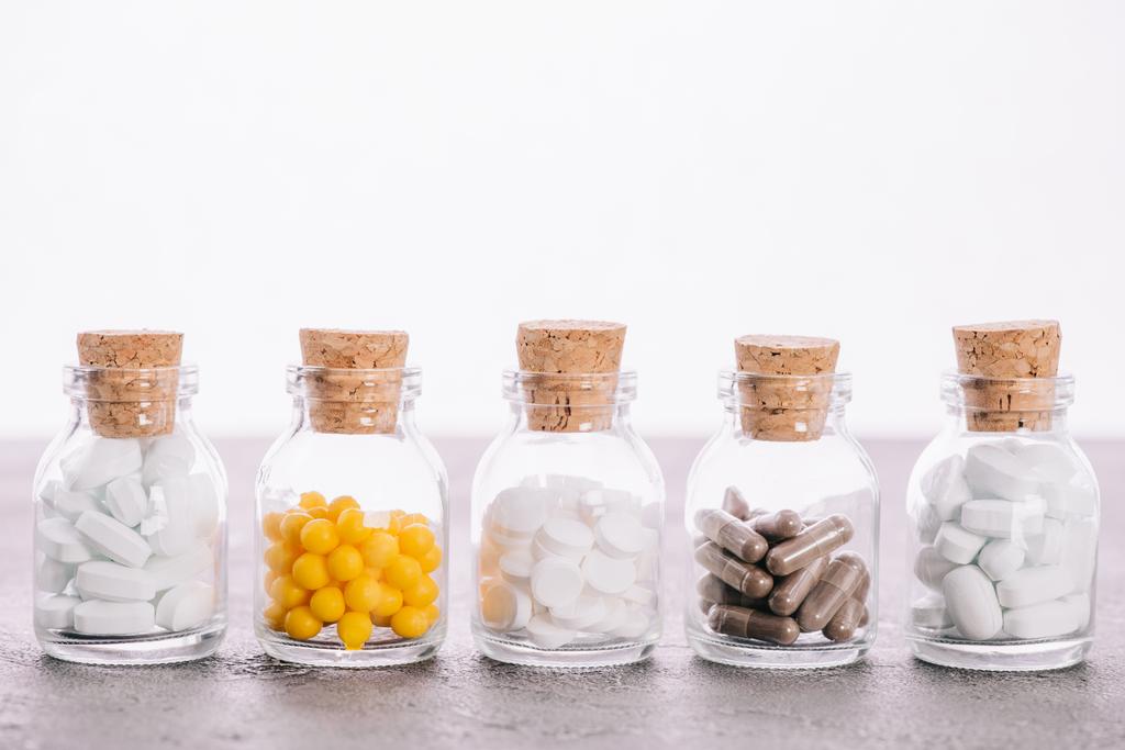 rangée de bouteilles avec bouchons et différentes pilules isolées sur blanc
 - Photo, image