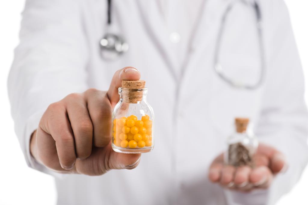 bijgesneden weergave van mannelijke arts weergegeven: fles met pillen geïsoleerd op wit - Foto, afbeelding