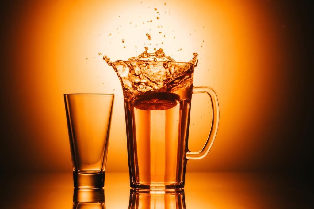 επιλεκτική εστίαση από γυαλί και τσαγιέρα με το τσάι και λεμόνι σε πορτοκαλί φόντο - Φωτογραφία, εικόνα