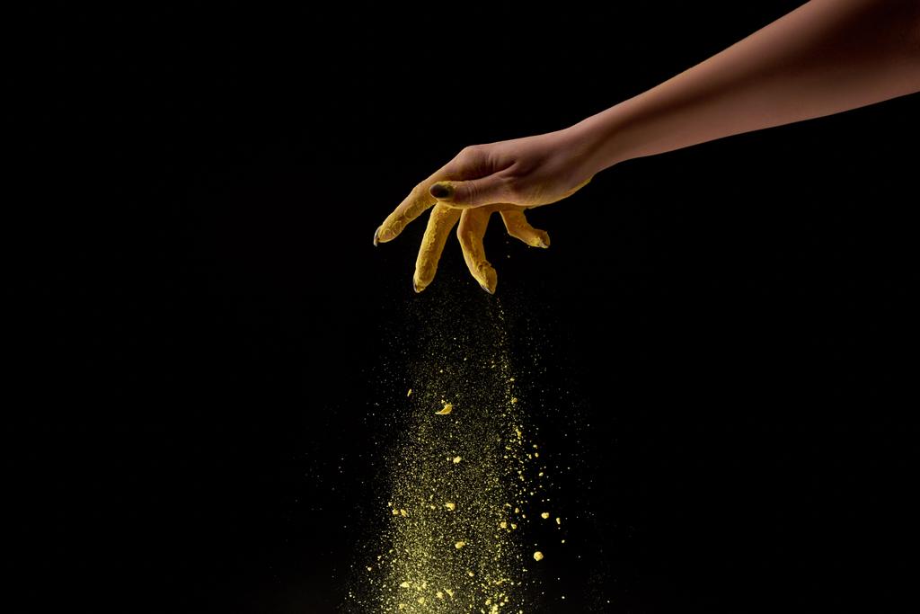 rajattu näkymä nainen ripottelemalla keltainen holi jauhe mustalla pohjalla
 - Valokuva, kuva