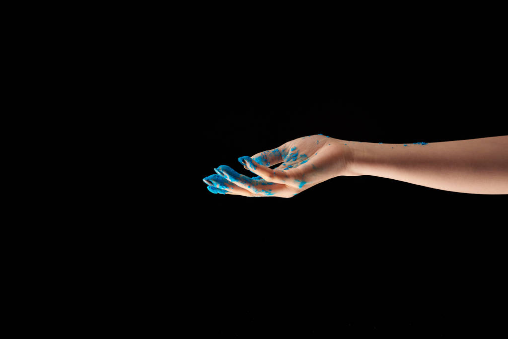 vista recortada de la mujer con polvo de holi azul en la mano aislado en negro
 - Foto, Imagen