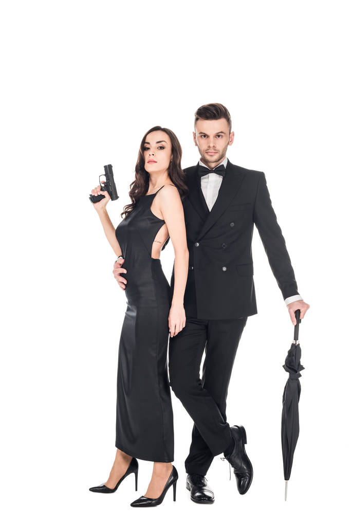 銃と白で隔離の傘を保持している黒い服を着た殺人者の美しいカップル - 写真・画像