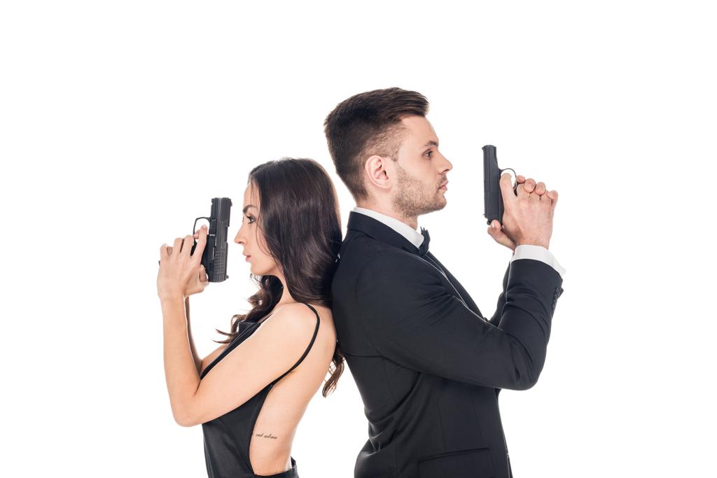 привлекательная пара секретных агентов в черной одежде, позирующих с оружием, изолированных на белом
 - Фото, изображение
