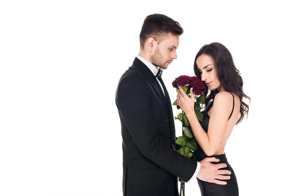 składania ofert para w czarne ubrania pozowanie czerwone róże na Walentynki, na białym tle - Zdjęcie, obraz