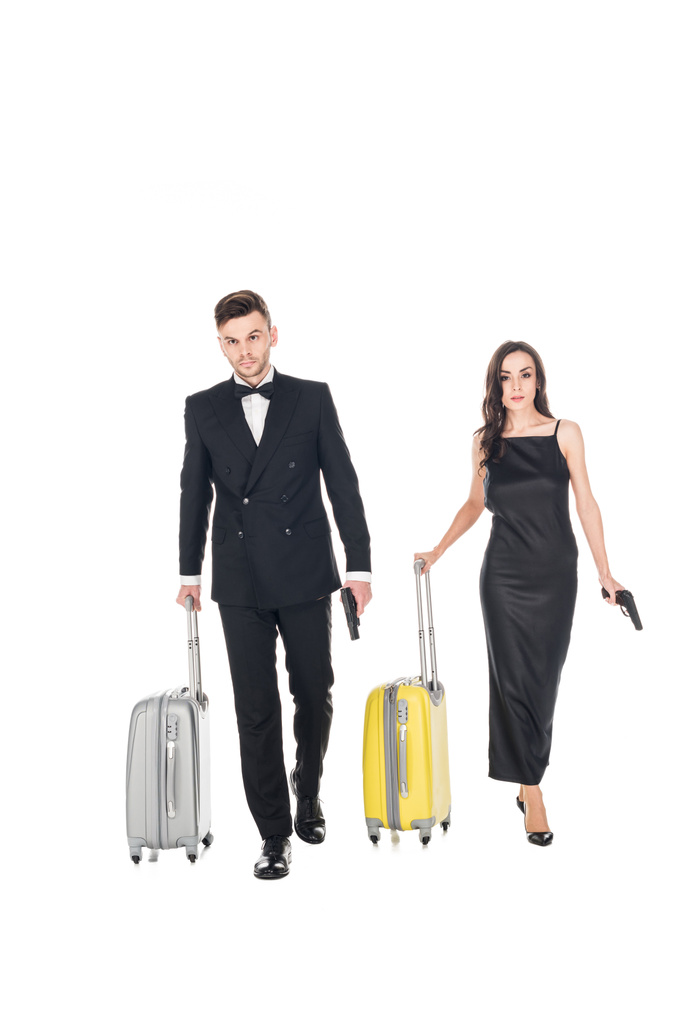 elegante pareja de agentes secretos vestidos de negro con pistolas y bolsas de viaje, aislados en blanco
 - Foto, imagen