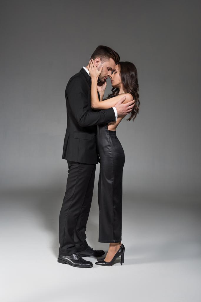 красива елегантна пара в чорному одязі, обіймається на сірому
 - Фото, зображення