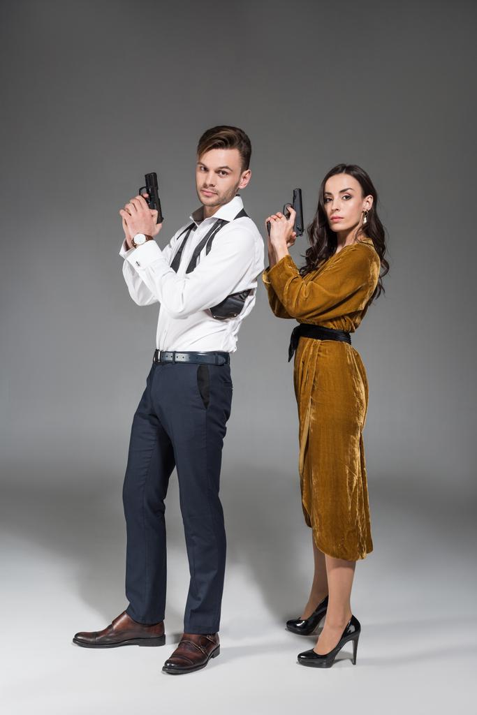 bella coppia fiduciosa di agenti segreti in posa con pistola su grigio
 - Foto, immagini