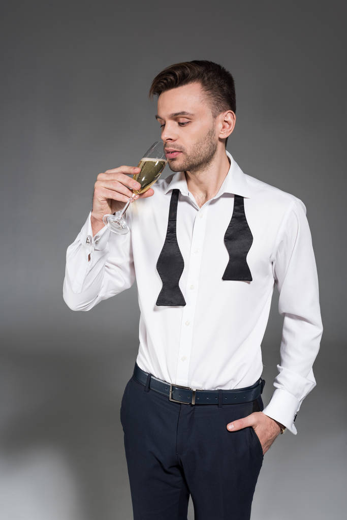 joven guapo bebiendo champán aislado en gris
 - Foto, imagen
