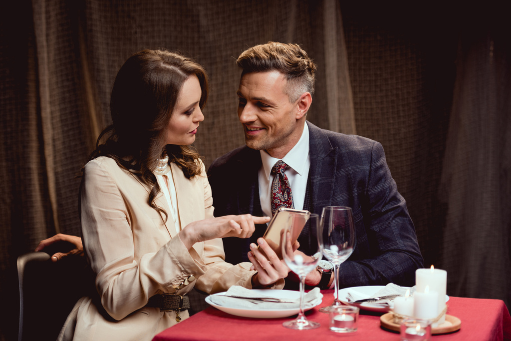 пара, сидящая за столом и использующая смартфон во время романтического свидания в ресторане
 - Фото, изображение