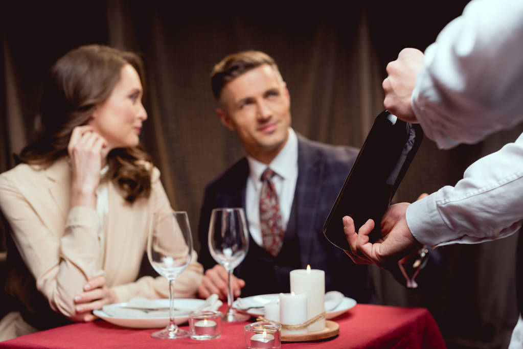 Selektywny fokus kelner wyświetlone butelki wina do para piękny podczas romantyczną randkę w restauracji - Zdjęcie, obraz