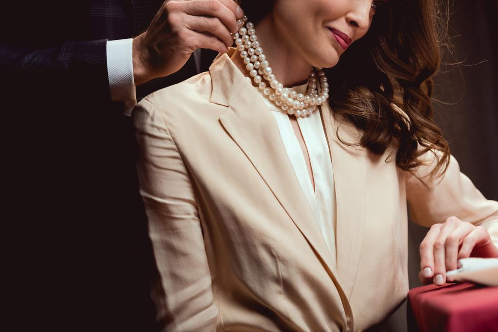笑顔の女性に真珠のネックレスを置く男のビューをトリミング ロイヤリティフリー写真 画像素材